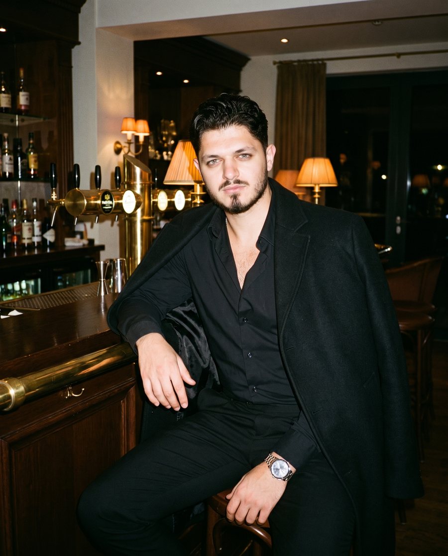 Arigon ganz in Schwarz an einer Hotelbar am Abend